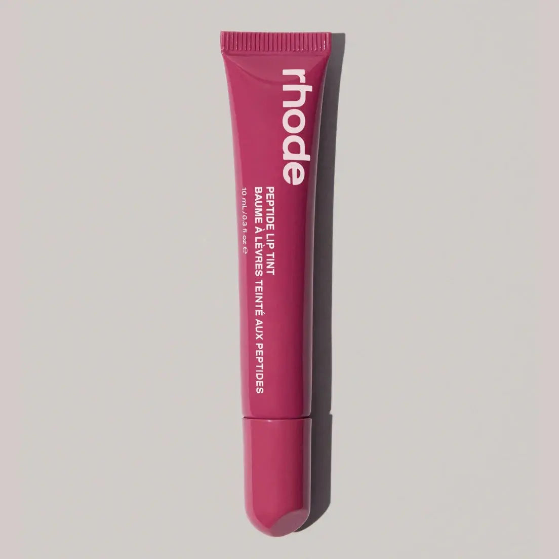 Rhode lip gloss tube in magenta fuchsia pink with open applicator tip