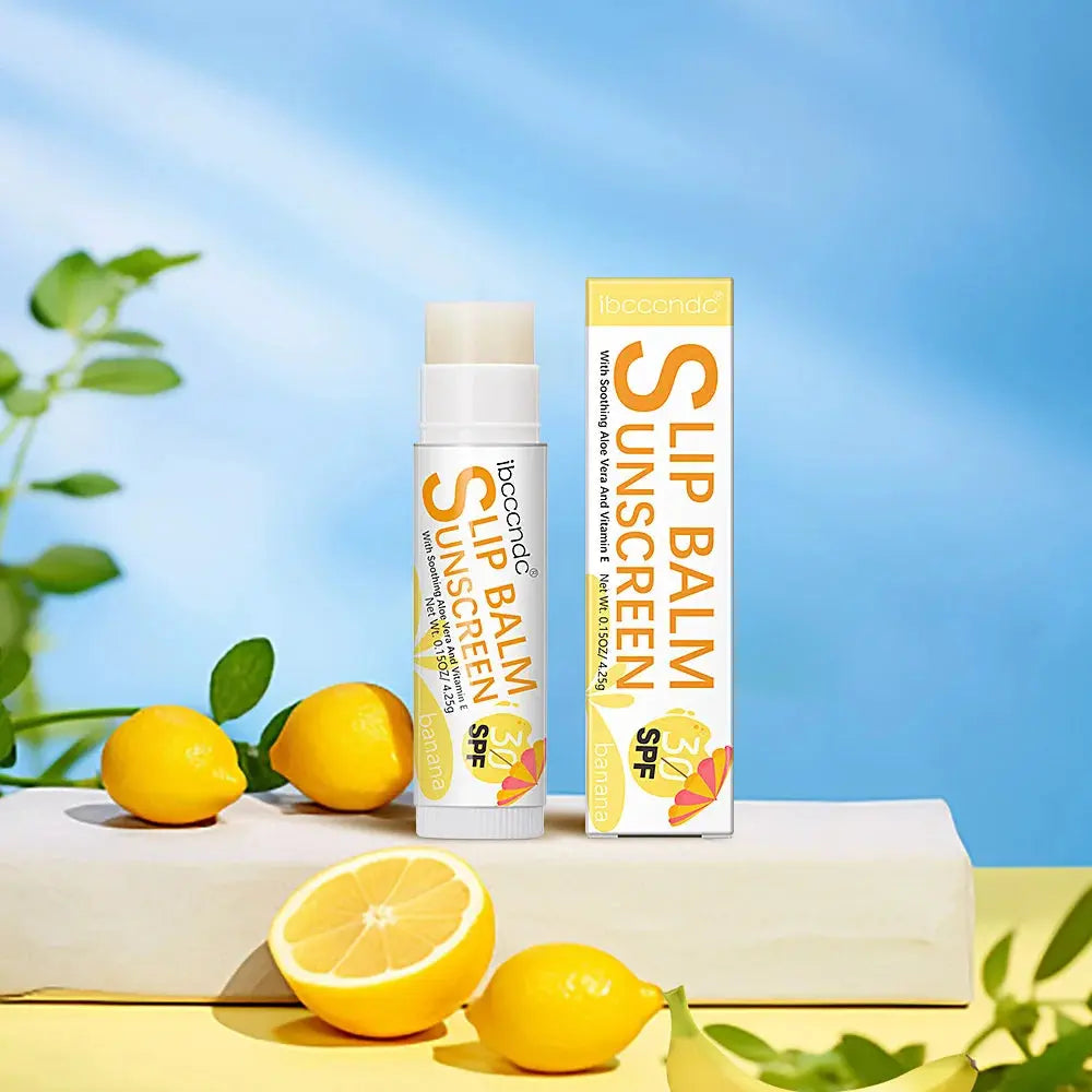 Banana lip balm SPF 30 stick with lemons and citrus on a tabletop