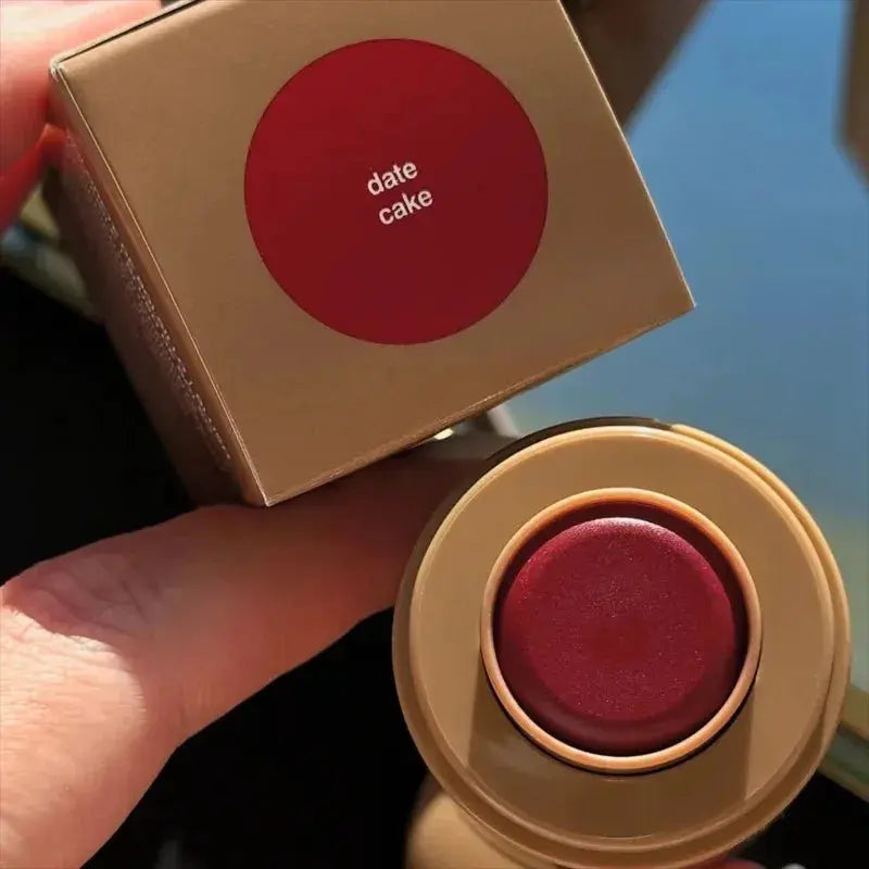 Lip glaze container with red-brown shade labeled "date cake"