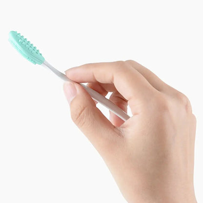 Hand holding a mint green silicone nose cleaning brush with white handle
