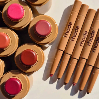 Assorted lip glaze tins and tubes, including pink and nude shades with caps on