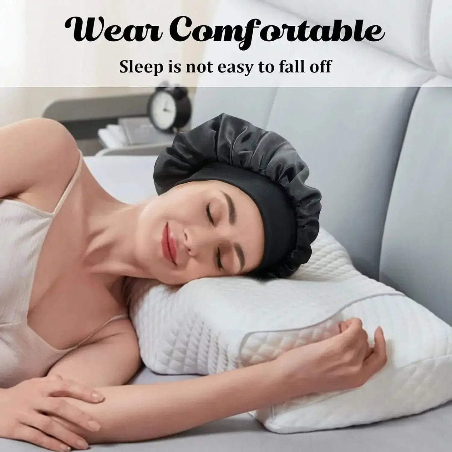 Satin sleep bonnet on woman lying in bed, wide brim and elastic band visible.