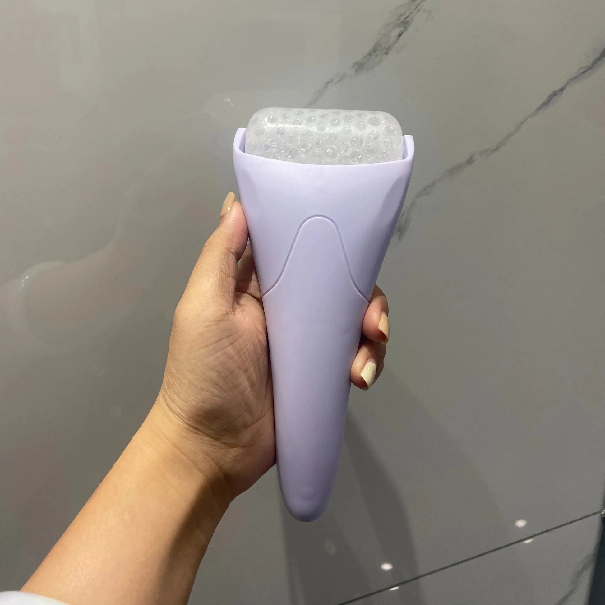 Purple handheld facial ice roller with frosty cooling head for face and eye massage