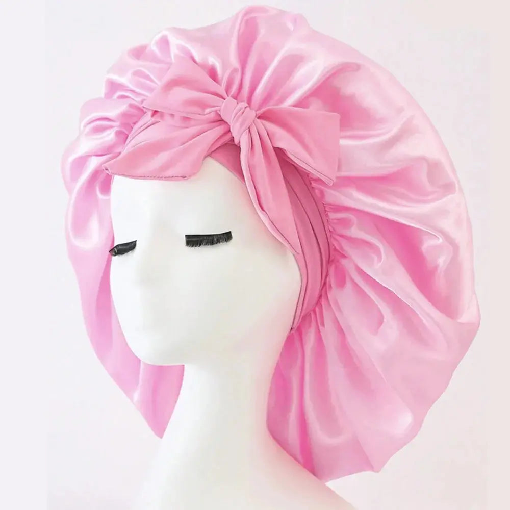 Light pink satin bonnet with gathered ruffles and front bow tie, adjustable band