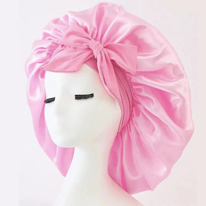 Light pink satin bonnet with gathered ruffles and front bow tie, adjustable band