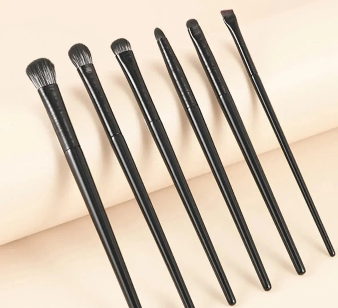 6 eye makeup brushes with dark handles and soft bristles, slightly spread arrangement
