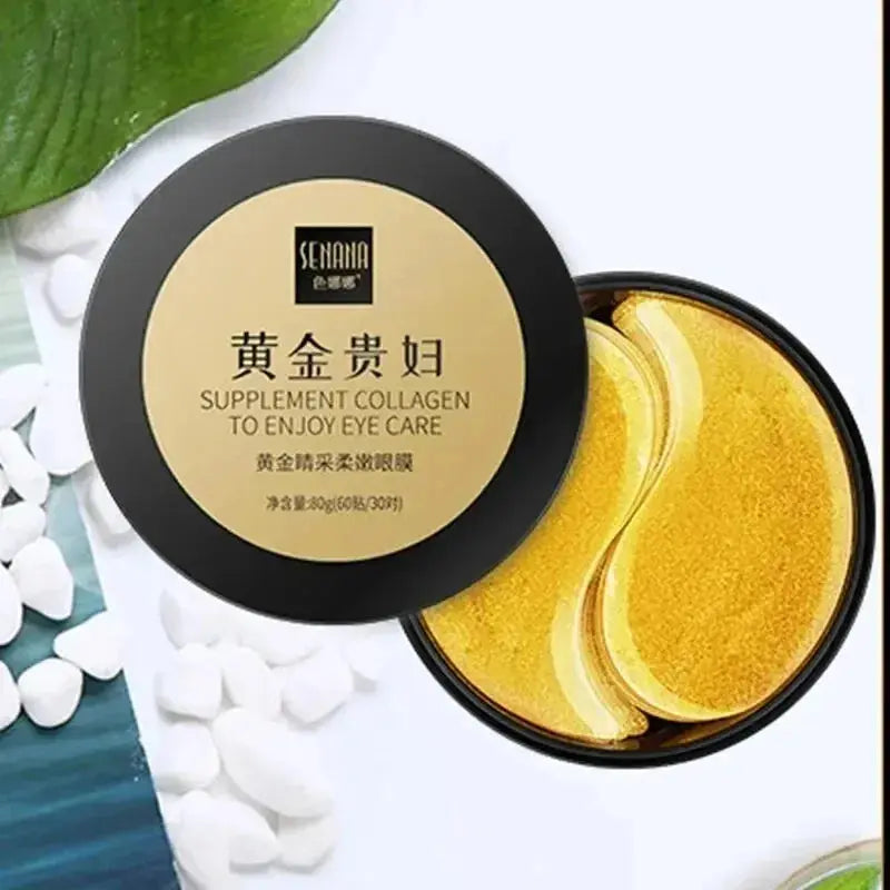 Golden eye mask jar with gold gel pads beside white pearls and green leaf