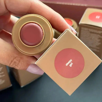 Pink lip glaze balm in round beige container with boxed color label