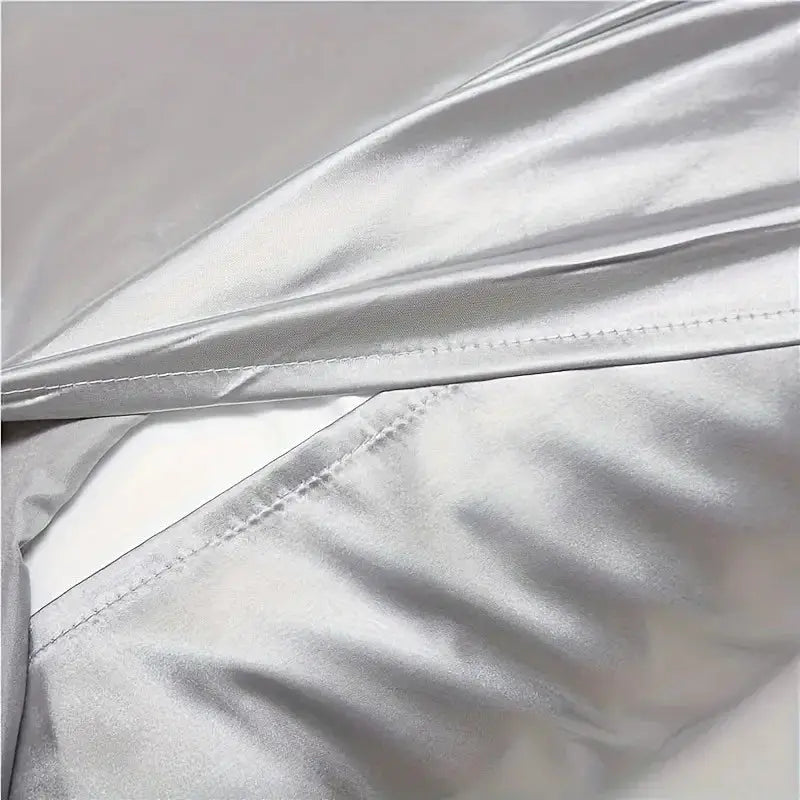 Light gray silk pillowcase close-up with stitched seam and smooth sheen