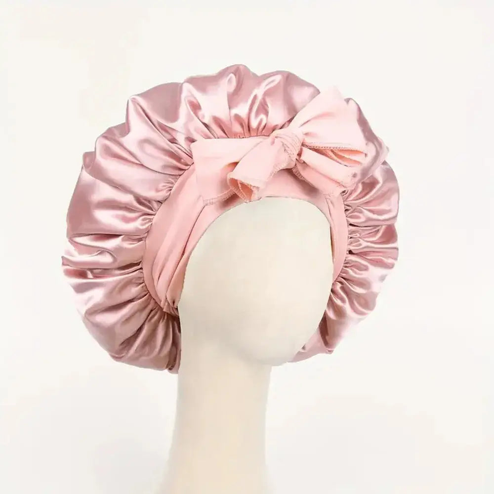 Soft pink satin bonnet with gathered ruffles and front bow tie, adjustable band