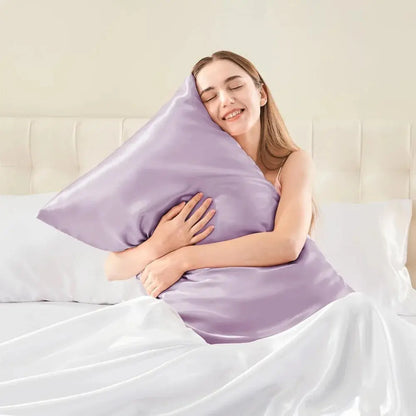 Lavender silk pillowcase held by a person on a bed with white bedding