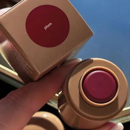 Plum-toned lip balm in round beige container, cap open